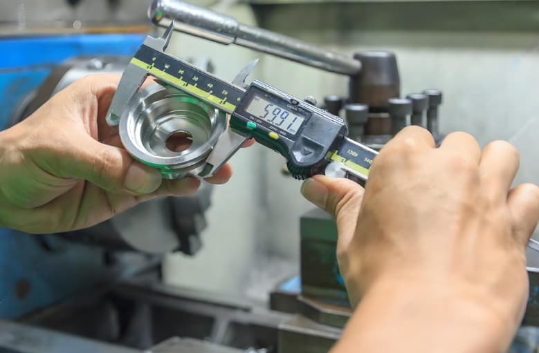 Technician using coordinate measuring machine (CMM) to inspect metal part for precision manufacturing quality assurance